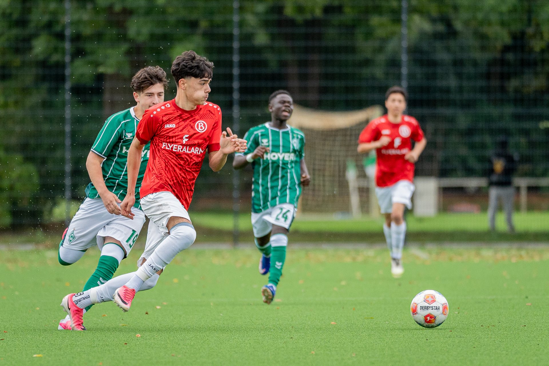 Spieler von ATS Buntentor im Laufduell mit einem Spieler von SV Werder Bremen