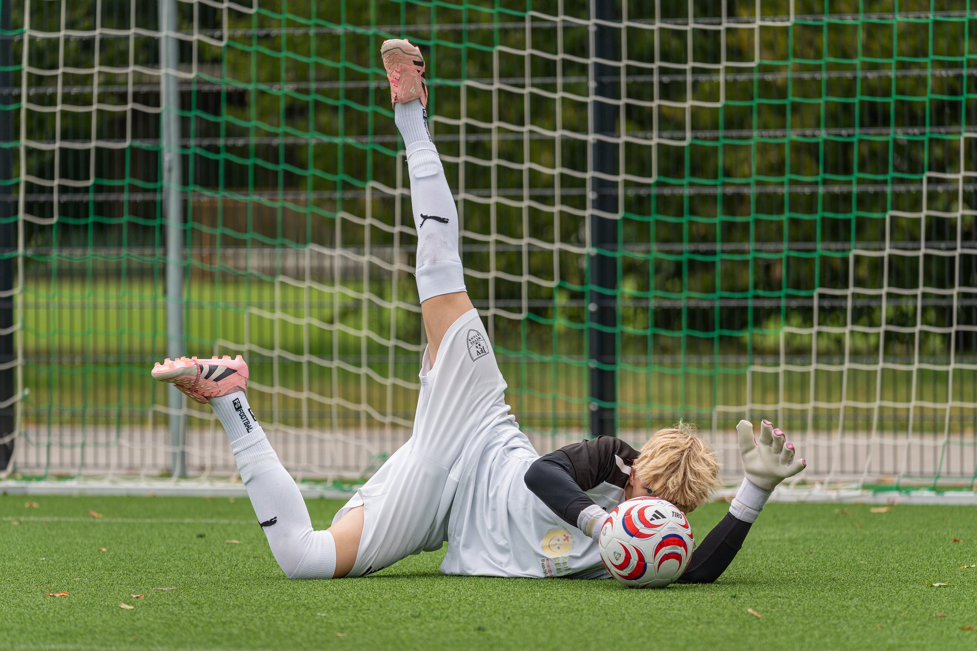 Torhüter von SV Werder Bremen liegt mit dem Ball vor dem Tor auf dem Rasen