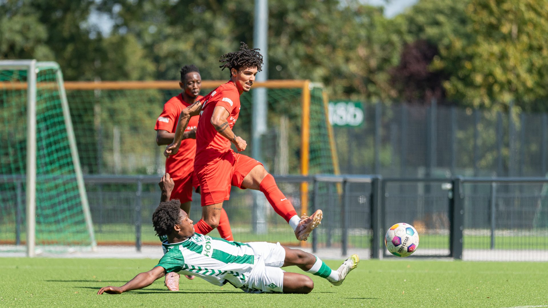 Fußballspieler springt über einen rutschenden Gegenspieler