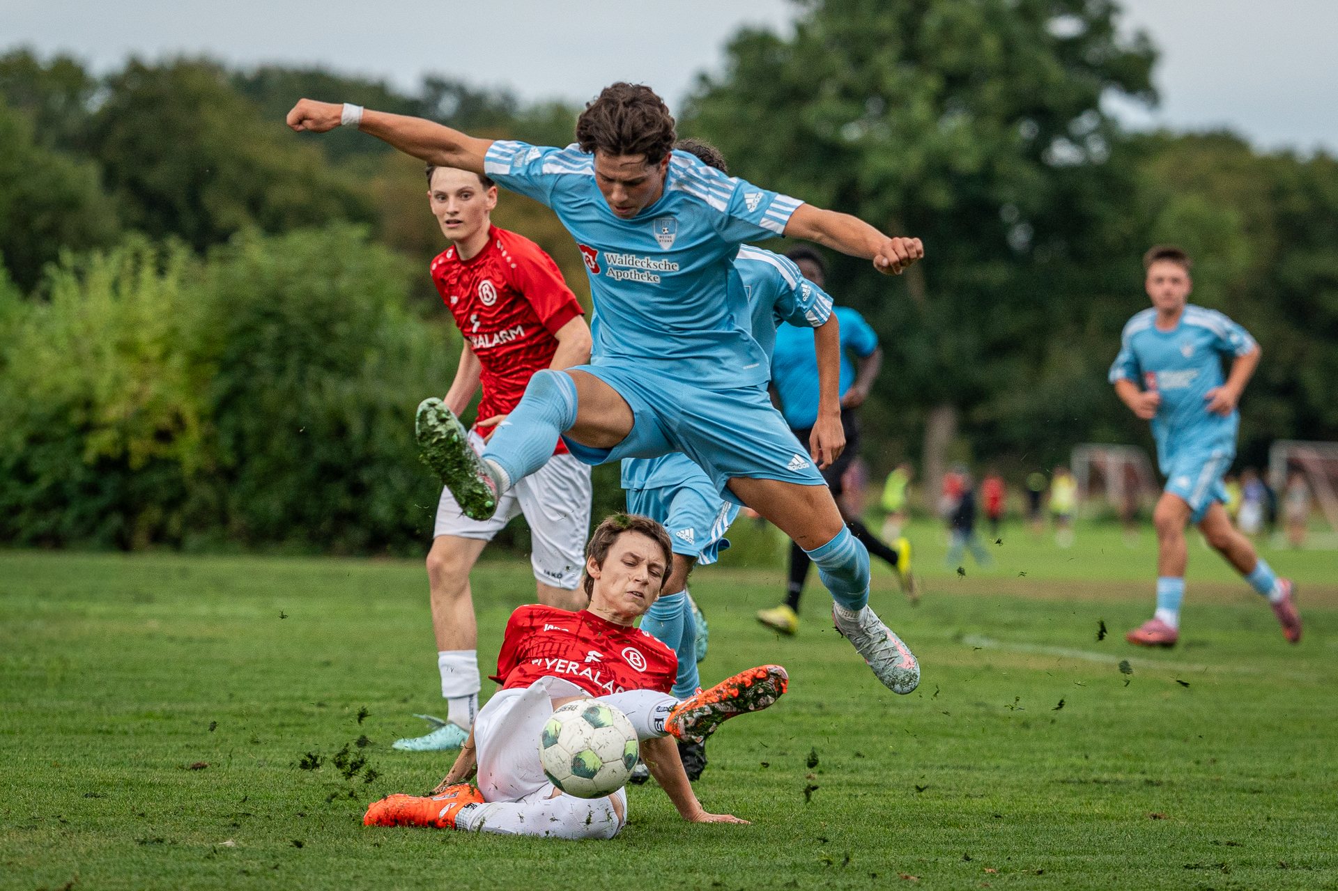 Spieler von JFV Weyhe-Stuhr springt über einen grätschenden Spieler von ATS Buntentor