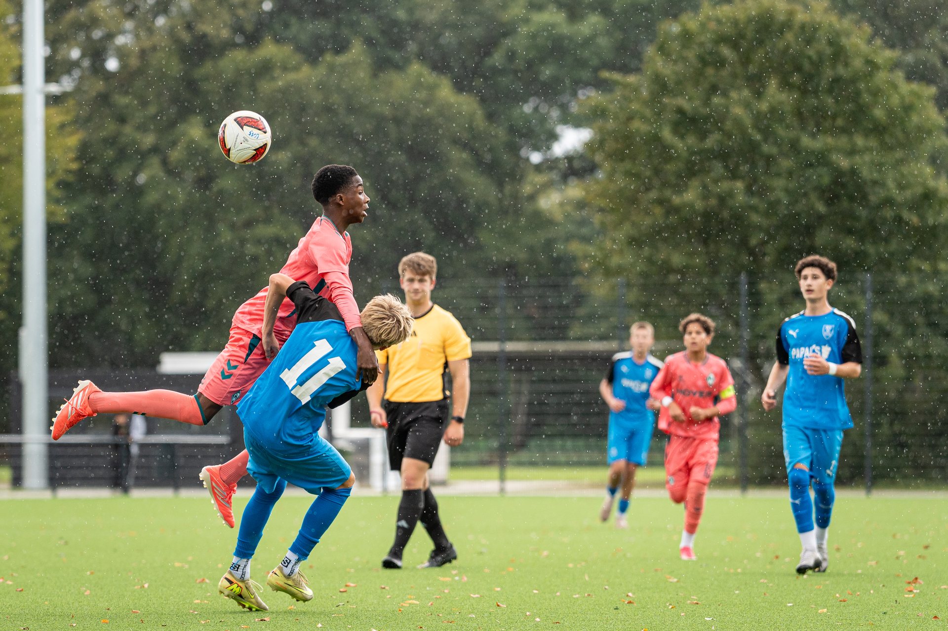 Spieler von SV Werder Bremen und JFV Weyhe-Stuhr im Kopfballduell bei Regen
