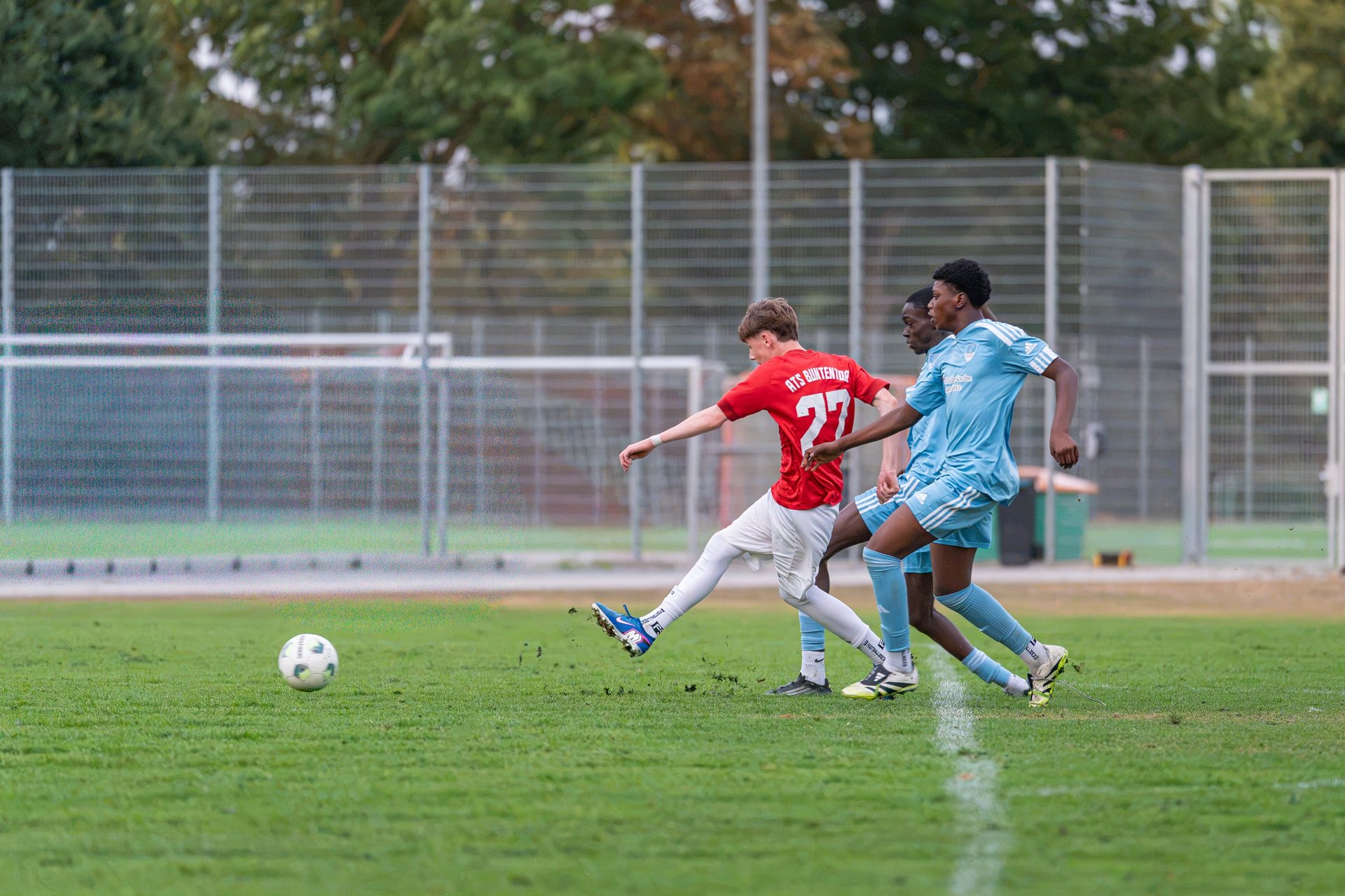 Fußballspieler bei einem Torschuss unter Bedrängnis mehrerer Gegenspieler