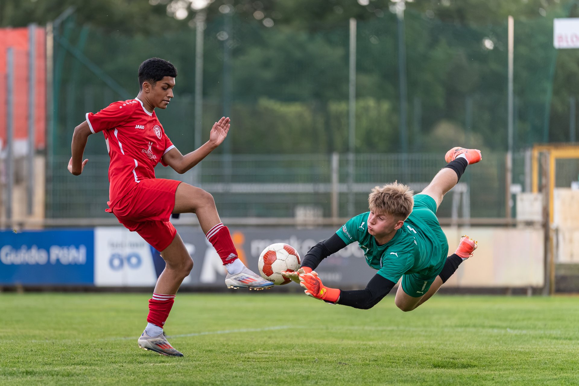 Fußballspieler im Duell mit einem heraushechtenden Torwart