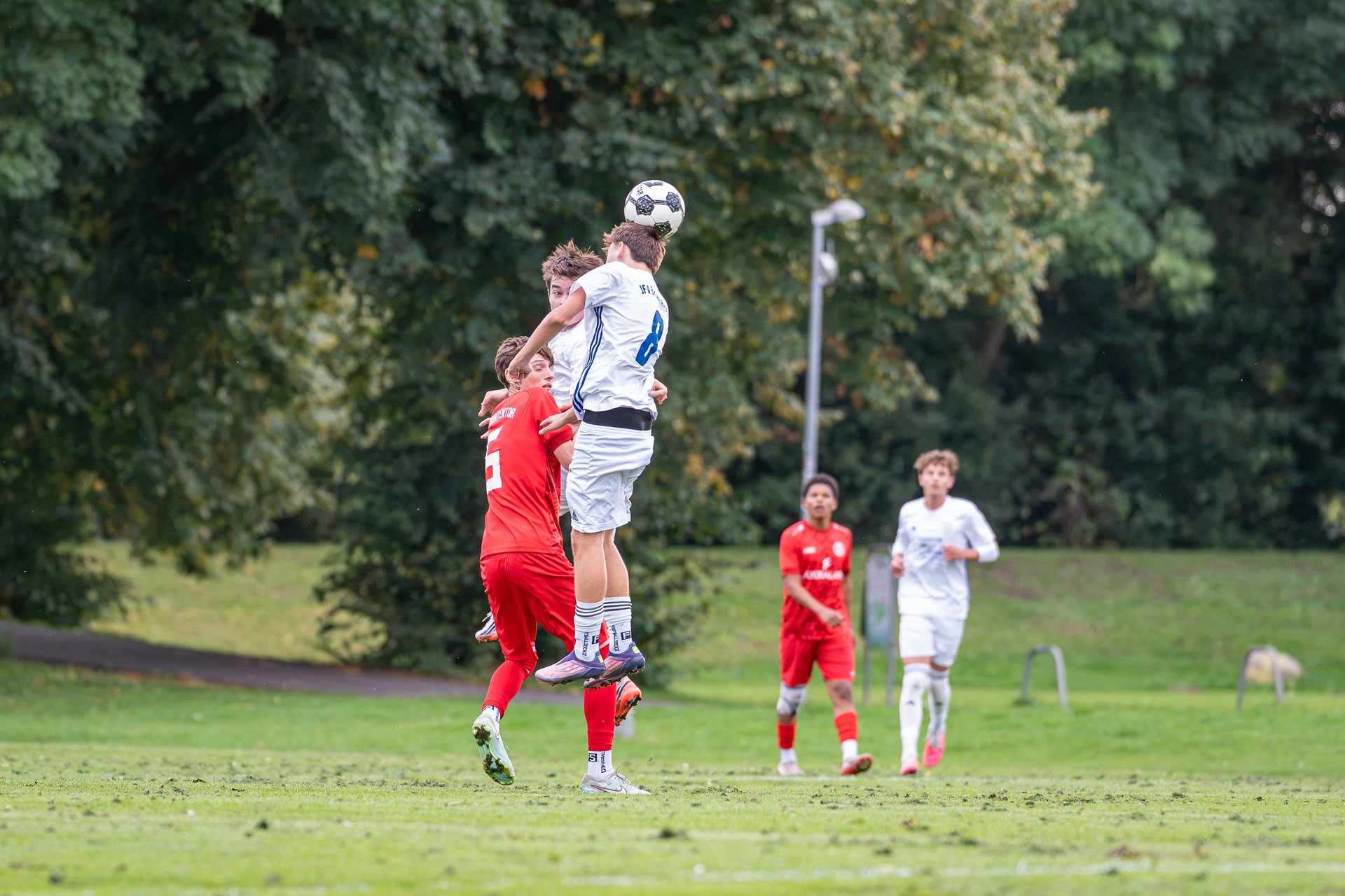 Spieler von JFV Bremerhaven springt neben Spielern von ATS Buntentor zum Kopfball hoch