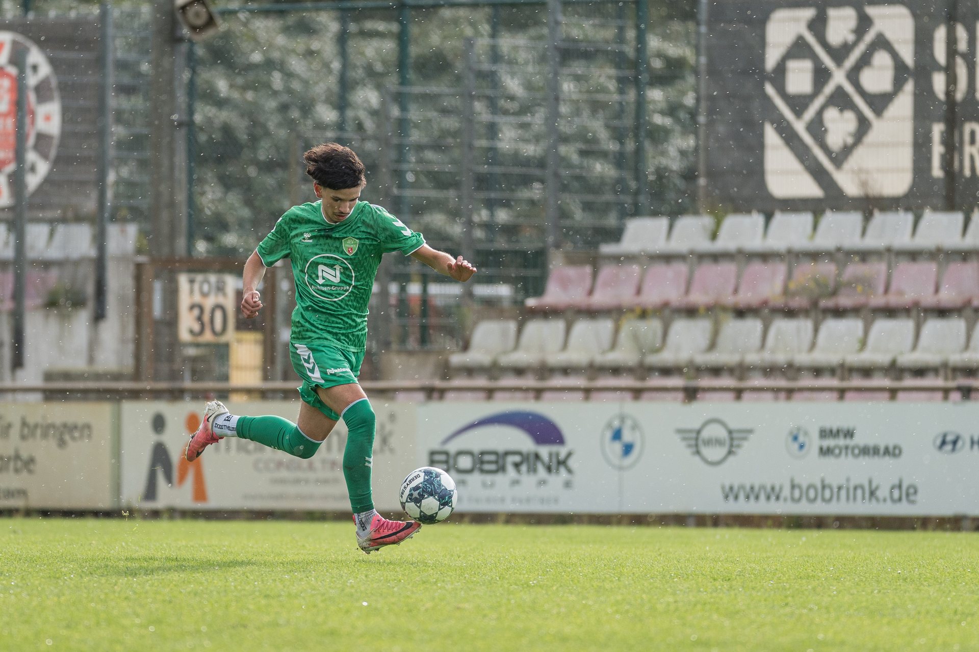 Spieler von JFV Bremen II kontrolliert den Ball mit dem Fuß vor der Tribüne