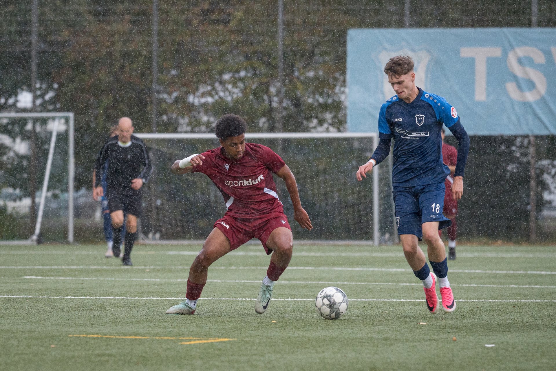Spieler des TSV Heiligenrode führt den Ball im Regen neben einem Spieler von JSG WuKo