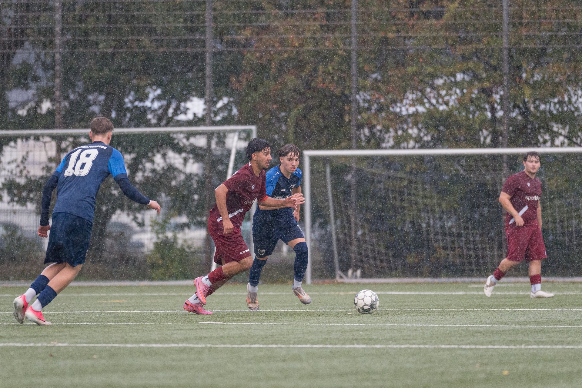 Spieler von JSG WuKo und TSV Heiligenrode laufen im Regen hinter dem Ball her
