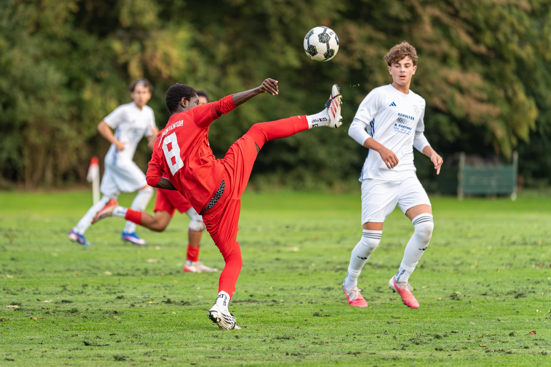 Spieler von ATS Buntentor streckt das Bein zum hoch fliegenden Ball neben einem Spieler von JFV Bremerhaven